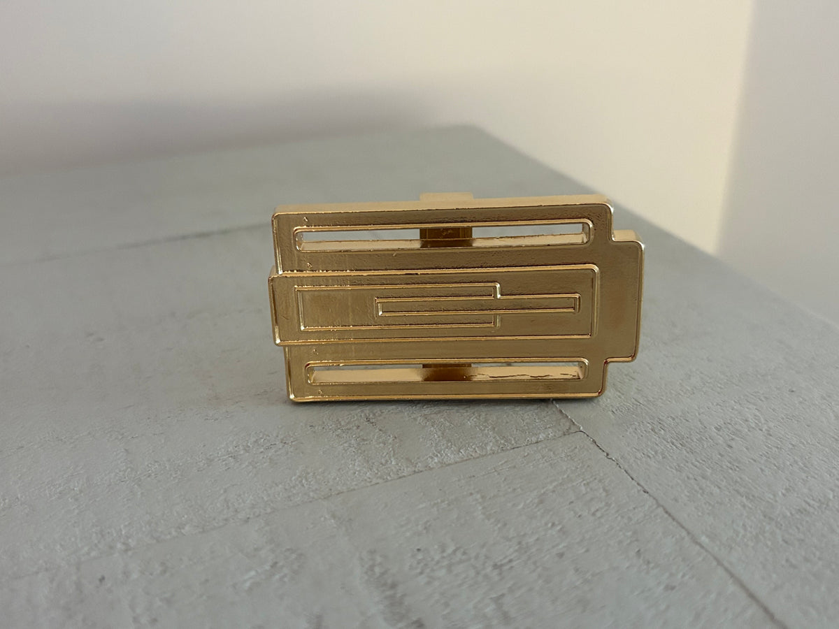 Hebilla bañada en oro brillante, hecha a mano en España, diseño exclusivo Zizhá para cinturones personalizables.